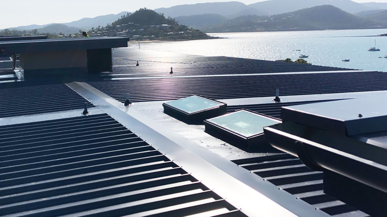 Dark metal roof with skylights, flashings and guttering overlooking the water